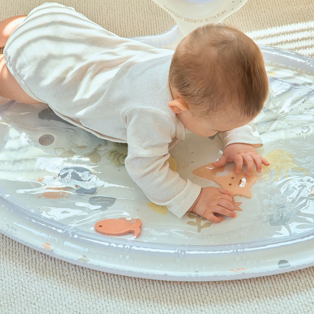 Baby playing on a transparent play mat with animal designs